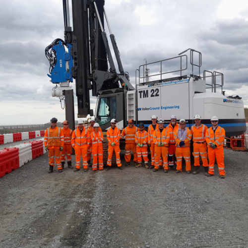 Picture of men in high vis stood in front of a piling rig.