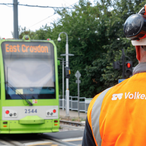 VolkerRail logo on back of a mans PPE with East Croydon tram in the background
