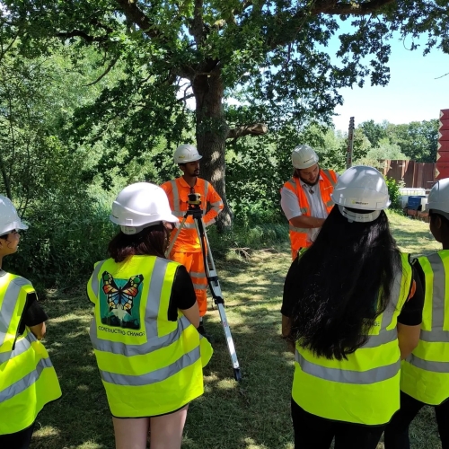 children stood on a construction site in yellow hi-vis jackets