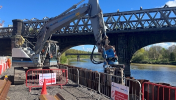 Picture of an excavator piling near a river.