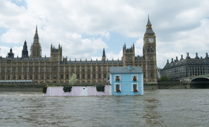House on pontoons floating on the River Thames in front of the Houses of Parliament