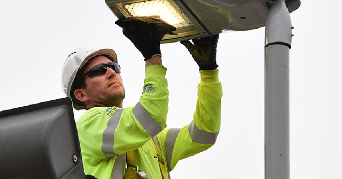 UK lighting technician replacing an LED lamp on an external light fitting