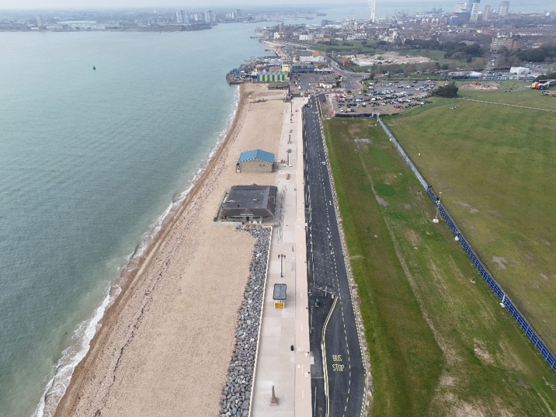 Aerial view of promenade of Southsea with beach and sea to the left and a green field to the right