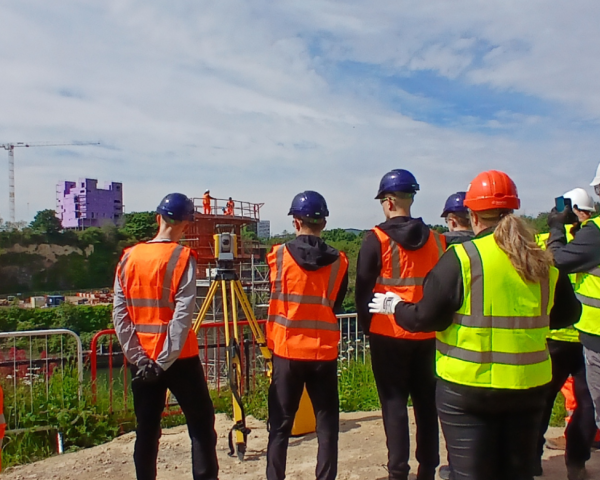 People in highvis on a site tour of the New Wear high-level Footbridge sign.