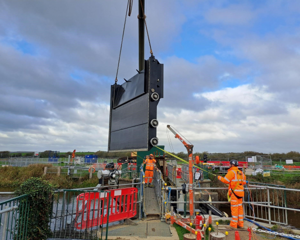Large flood gate being lifted into position on construction site
