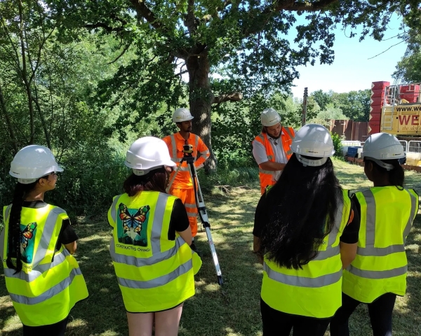 children stood on a construction site in yellow hi-vis jackets